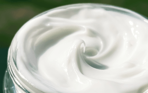 The best face moisturizer for women, cream for aging, and extra dry skin. Shop Moisturizers. White moisturizer in a jar on a green background.