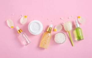 Shop skincare. Skincare products and flower petals on a pink background.
